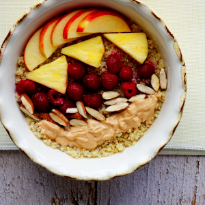 quinoa with sliced apples, pineapples, strawberries, almonds and peanut sauce